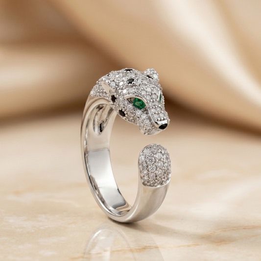 Silver panther-shaped ring with gemstones on a beige background