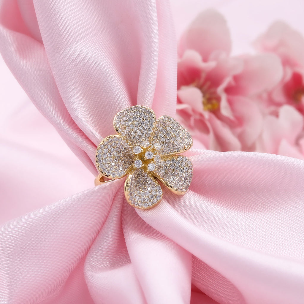 Gold flower-shaped jewelry on pink fabric with a blurred floral background