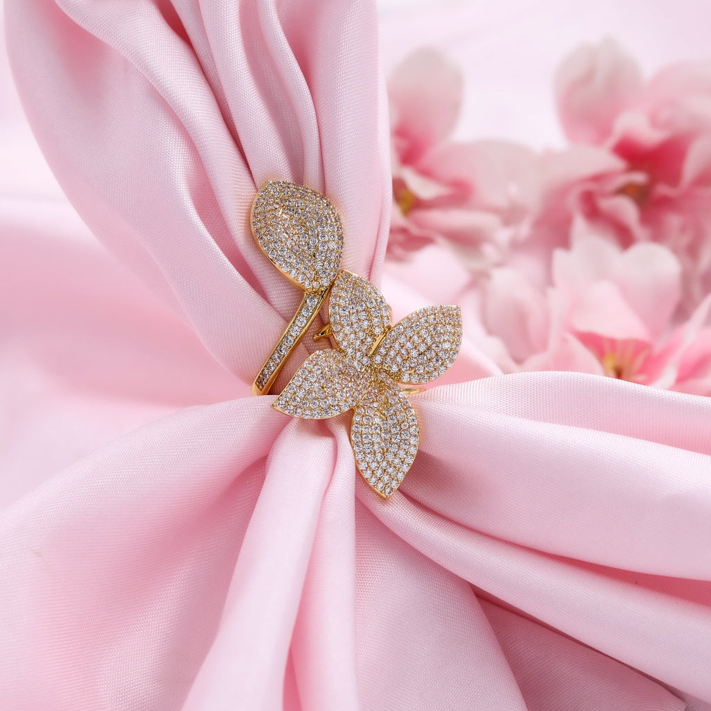 Gold flower-shaped jewelry on pink fabric with flowers in the background