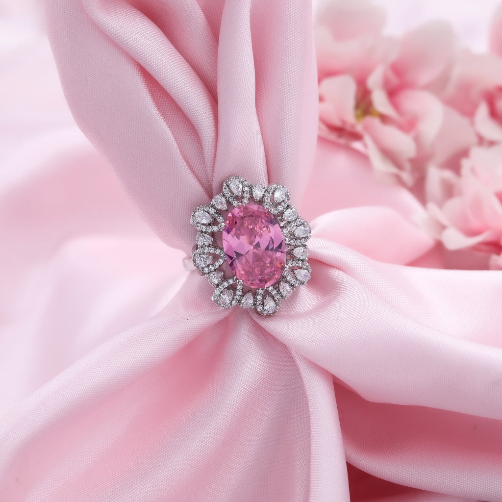 Pink gemstone brooch on pink fabric with a blurred floral background