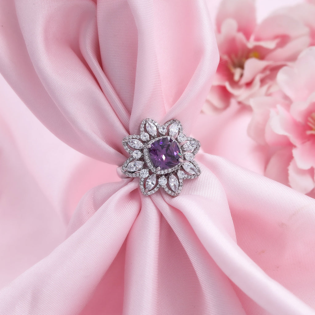 Purple gemstone ring on pink fabric with floral background