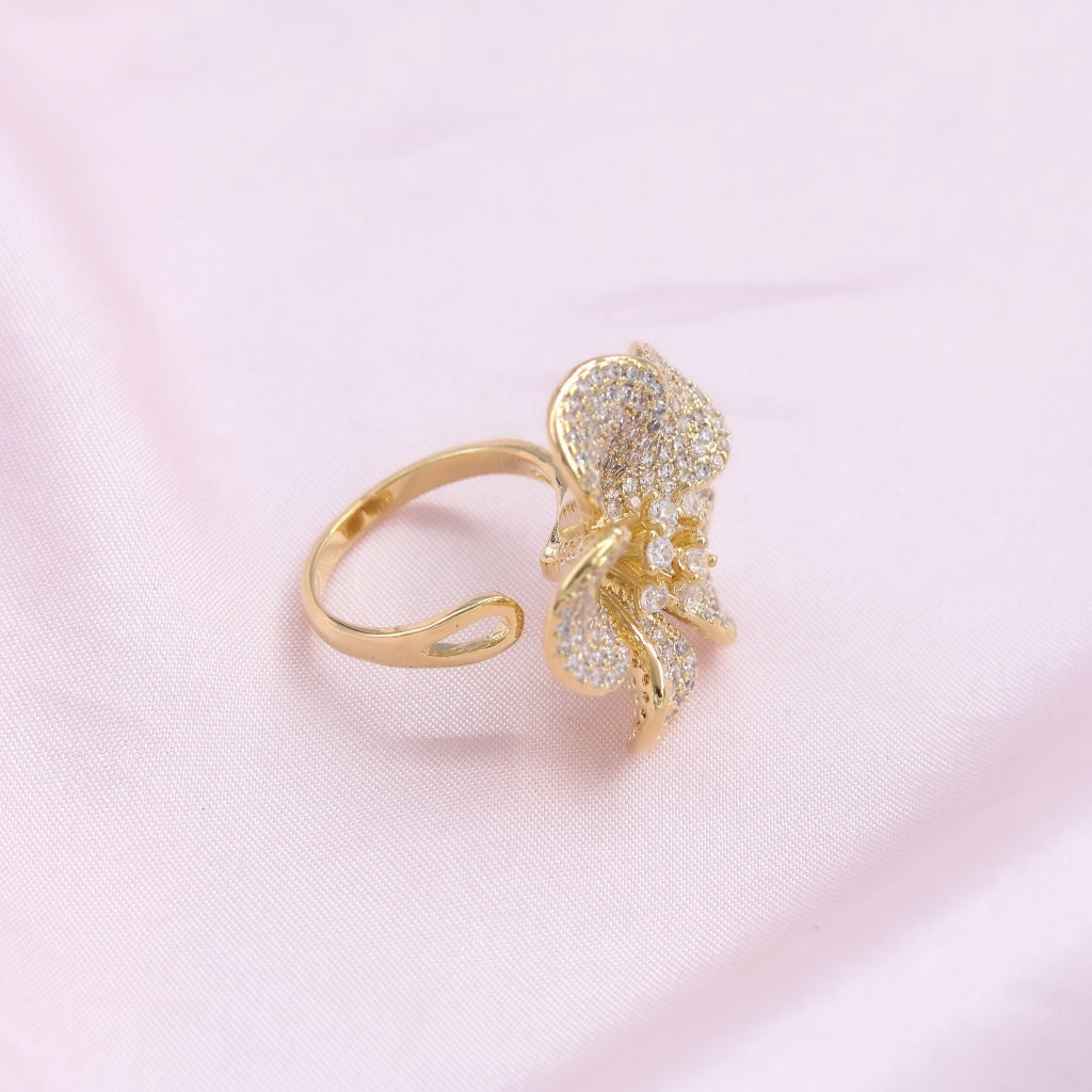 Gold ring with floral design on a pink background